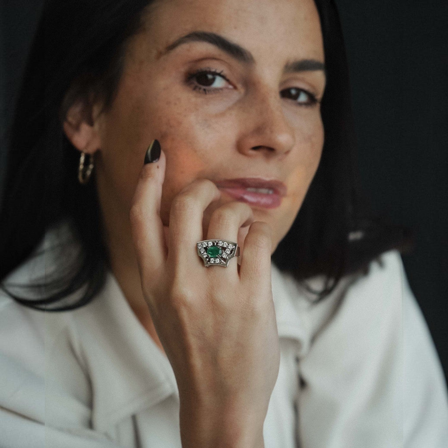 Menina Amsterdam Veyla 14K gold statement ring featuring a central emerald surrounded by brilliant-cut diamonds.