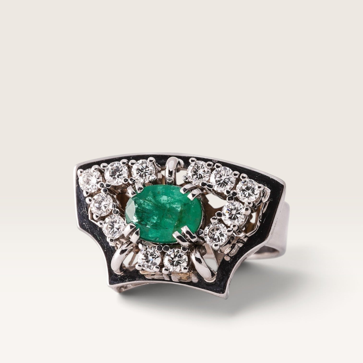Menina Amsterdam 14K white gold statement ring featuring a central oval emerald surrounded by brilliant-cut diamonds.